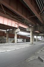 Street scene of an urban underpass under a flyover with a deserted road devoid of cars and people