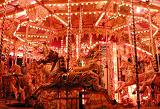 Close up of an illuminated carousel at a funfair or amusement park with decorative horse rides