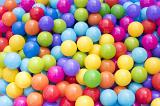 Pit filled with brightly coloured plastic balls on a fairground in a close up full frame view in the colors of the rainbow