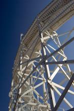 Looking up at the structure of a Big Dipper rollercoaster at an amusement park with a view up to the track against a blue sky