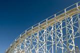 A low angle of an overhead roller coaster track and clear, blue sky.