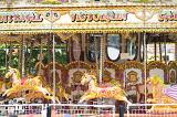 An empty amusement park ride with gold, carousel horses.