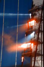 Banks of spotlights on a tower at a circus lighting up the performers below shining through a smoky atmosphere