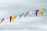 String of colorful triangular bunting flying against a cloudy grey sky with copy space conceptual of celebration, festival or party