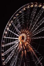 Close up on a giant ferris wheel with gondolas to ride at an amusement park of fairground illuminated at night