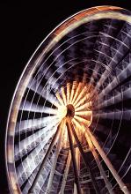 Spinning ferris wheel with motion blur illuminated at night for a thrilling ride at an amusement park of fairground