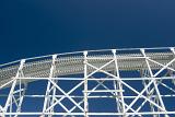 Low angle view of the track of a Big Dipper roller coaster looking up at the crest of a hill against a blue sky