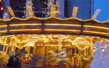 Motion blur of a festive merry-go-round or carousel illuminated at dusk on a fairground or amusement park