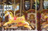 A close up of horses on a traditional merry-go-round carousel at an amusement park.