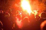 People watching a roaring bonfire with flames shooting into the air on Bonfire Night or Guy Fawkes as they celebrate the festival