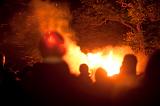 Spectators watching a blazing bonfire with orange flames shooting into the air on Bonfire Night or Guy Fawkes