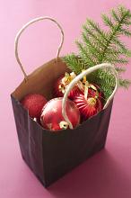 Bag full of colorful Christmas decorations with red baubles and pine branch over a red background