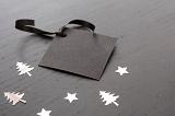 Plain black gift tag with space for text and surrounded by silver christmas shapes