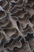 Christmas pastry cutters of different traditional shapes arranged on a wood background in a full frame view conceptual of holiday baking