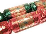 Close Up of Two Festive Foil Wrapped Christmas Crackers with Poinsettia Patterned Paper on White Background