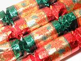 Festive green and red Christmas crackers in foil with a pattern of Xmas poinsettia for decorating the seasonal table, close up background view