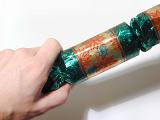 Close Up of Hand Pulling Christmas Cracker Open Over White Background