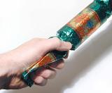 Man pulling a colorful Christmas cracker with a friend during a festive celebration to see who wins the treat inside, closeup of his hand over white