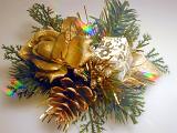 Gold themed festive bundle with a rose, pine cone and small Christmas gift in green foliage, close up view