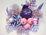 A Silver coloured decortative christmas sprig with pink and purple coloured berries and balls