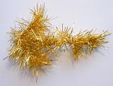 Length of festive gold tinsel for a Christmas celebration lying on a white background with copyspace for your seasonal greeting, close up view