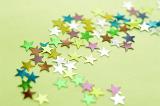 Multi-Colored Star Shaped Stickers Scattered on Green Background, Full Frame for Backgrounds