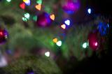 Festive Christmas evergreen tree ornated with decorative purple baubles and heart shaped lights, close-up with bokeh effect