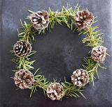 Traditional fresh homemade rustic holiday wreath made of green pine foliage and cones on a dark background with copy space