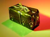 Small Christmas present in colorful lighting wrapped in star decorated paper and tied with gold string