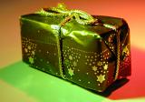 Small Gift Wrapped in Star Patterned Paper and Gold Rope Lit Dramatically with Green and Red Light