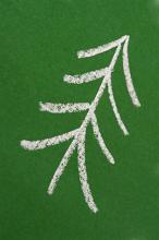 Simplistic childlike hand-drawn chalk pine tree on a green chalkboard, diagonal orientation