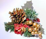 Close up of Christmas decoration with sprigs of pine tree, holly leaves, pine cone, festive red flower and faux berries with gold spray paint on white background