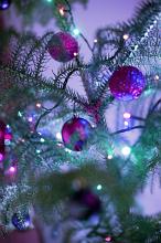 Purple themed Christmas celebration with colorful purple glitter baubles and sparkling lights on a tree over a purple background