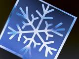Close up of blue and white snow flake on blue square, black background