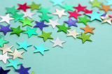 Background Image of Colorful Metallic Star Shaped Stickers Scattered on Light Blue Background with Copy Space