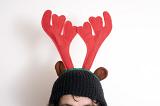 Person wearing a decorative Reindeer hat with red antlers for Christmas in a close up cropped view on the hat