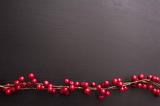 Xmas berry border with festive red berries over a dark grey background with copy space for a holiday greeting