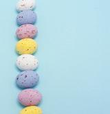Easter Egg Border. Line of speckled candy Easter eggs on a blue background with copyspace.