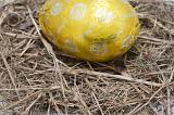 Colourful yellow foil wrapped chocolate Easter Egg on straw with copyspace