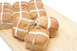 Wooden board with batch of fresh hot cross buns for Easter