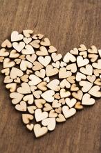 Heart shape composed of many small little wooden hearts conceptual of Valentines Day, love, romance, anniversary or wedding on a wood background
