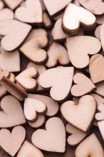 Pile of unpainted wooden hearts full frame vertical background concept