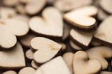 Pile of wooden hearts cut out of unpainted plywood, close-up selective focus full frame background image concept