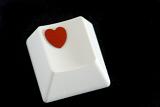 a computer key with a heart symbol on a black backdrop, concept of online or computer dating or sending a romantic e-mail