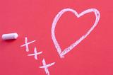 a love heart symbol and three chalk kisses hand drawn on a pink tinted surface