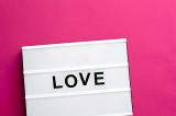 Love message lightbox with changeable black letters on white table box over pink background with copy space