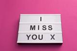 Message I MISS YOU X written with changeable black letters on white lightbox on pink background. Missing ex concept
