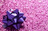 Close-up full frame image of glossy purple ribbon on gift box covered with pink glitter