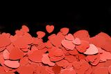 a background or bottom border of red metallic heart shapes on a black backdrop