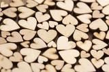 Scattered wooden hearts Valentines background arranged in a random pattern of different sizes viewed obliquely with shallow dof